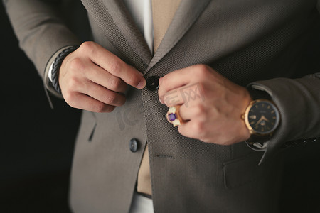 一个男人穿上结婚礼服并系上纽扣