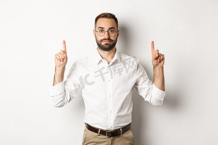 商打折促销海报摄影照片_留着胡须的年轻商人竖起手指，展示促销优惠，站在白色背景上
