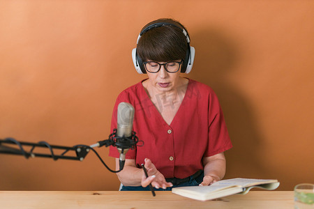 中年女电台主持人对着麦克风讲话和阅读新闻 — 电台广播在线概念