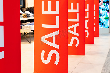 销售商业海报摄影照片_服装店入口处的销售标志，大红板白字。
