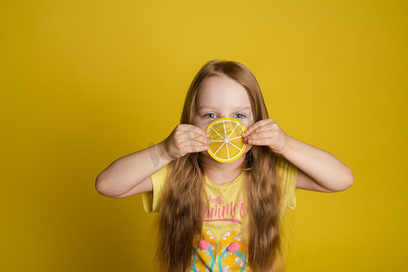 微笑的小女孩的画像，近眼拿着一片柠檬，看着相机中特写