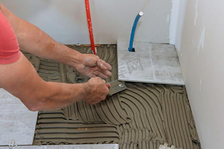 拖拉机的人摄影照片_将陶瓷地砖放在粘合剂上的位置的人
