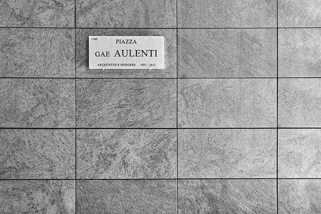 designer摄影照片_带有标志的天然灰色花岗岩瓷砖墙 - Piazza Gae Aulenti, architetto e designer - 意思是 Gae Aulenti 广场，建筑师和设计师。 