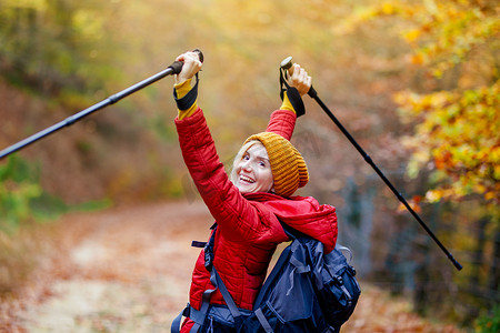 一直在路上摄影照片_带着杆子和背包在小路上徒步旅行的女孩。