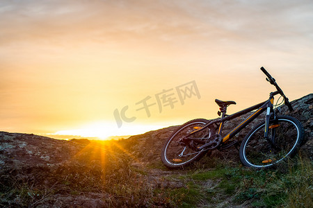 日落时在岩石小道上骑山地自行车。