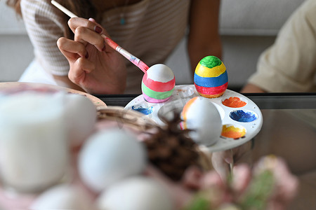 拿着彩蛋摄影照片_年轻女子拿着画笔和彩蛋，为复活节做准备的镜头。