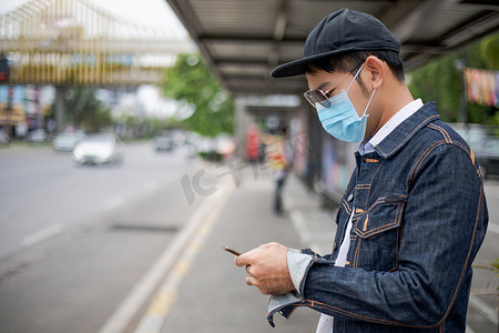 亚洲年轻人在城市使用智能手机，戴着脸 m