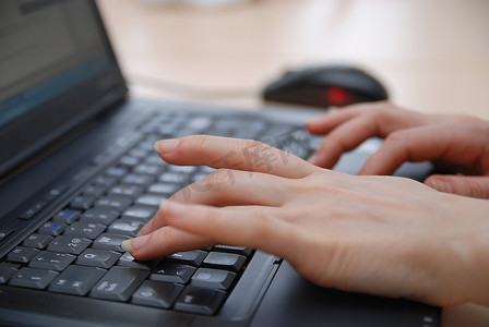 女人的手在笔记本电脑键盘上打字