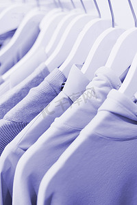 2022 年紫色的衣架和陈列柜上的衣服。高领毛衣、T 恤、毛衣、运动衫颜色非常鲜艳。