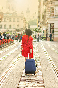 美丽的年轻女孩带着蓝色手提箱走路。