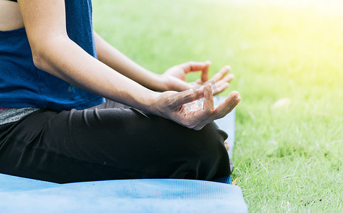 一个在户外做冥想瑜伽的女孩的手的特写，在草地上做瑜伽的手的特写