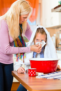 孩子流鼻涕摄影照片_母亲用蒸气浴照顾生病的孩子