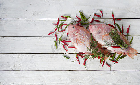 生鲜的粉红色罗非鱼放在一块板上，上面撒着小红辣椒