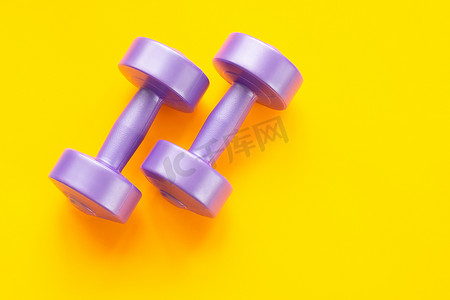 主题紫色摄影照片_黄色背景上的两个紫色哑铃