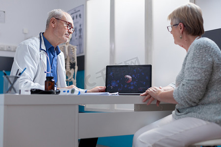 医生在笔记本电脑上向柜子里的病人展示冠状病毒细菌图解
