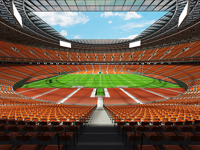vip座椅摄影照片_大型美丽的现代橄榄球体育场，配有橙色座椅和 VIP 包厢
