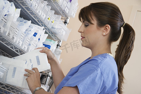女护士站在架子上，手里拿着药品