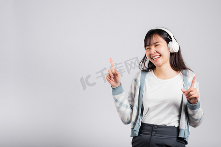 女人兴奋地笑着用蓝牙耳机听音乐广播，用智能手机跳舞