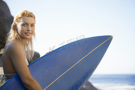 海边携带冲浪板的美丽年轻女子的肖像