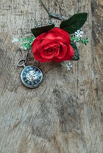 红玫瑰花和旧木板背景上的复古怀表。