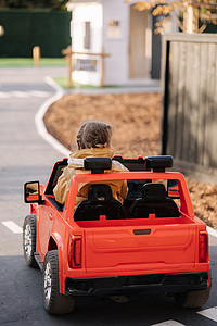 可爱的小女孩骑着红色电动吉普车在迷你城市里行驶。