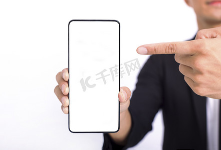 商人手持白色空白屏幕的大智能手机，靠近相机展示并指向设备