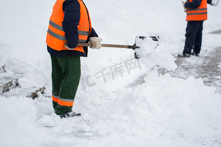 特殊形式的市政服务员工正在用铲子清除人行道上的积雪