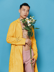 韩国一束花摄影照片_穿着黄色外套和粉色裤子的一束鲜花的韩国男性形象