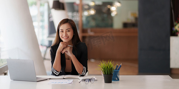 离职申请单摄影照片_女商人手持笔在笔记本电脑上查看银行储蓄账户申请。