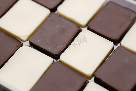 灰色背景中盒子里的黑巧克力和白巧克力