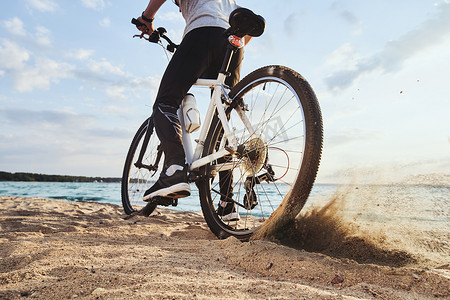 沿着海岸线行驶的男性骑自行车者。