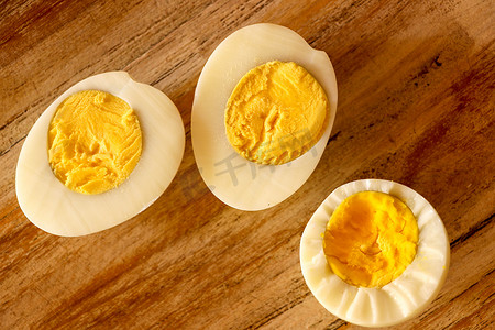 煮熟的鸡蛋，在木质背景上切成两半