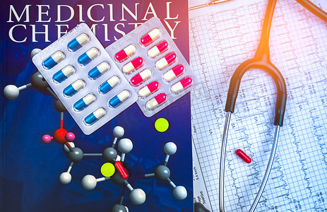 药物化学教科书和听诊器上的药丸放在心电图或心电图（心电图）图表报告纸上。