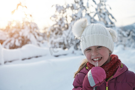 可爱的小女孩在美丽的冬日吃冰柱