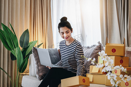 网上销售的经营理念，一个漂亮的女孩正在使用电脑检查订单，根据收到的客户订单向客户派送包裹。