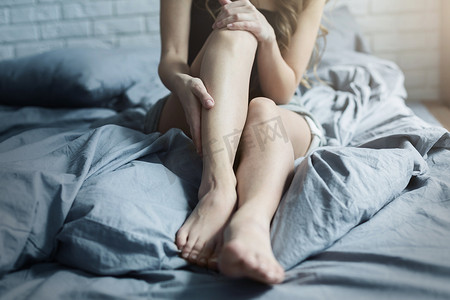 女性疲惫摄影照片_女性疲惫的双腿躺在家里的床上