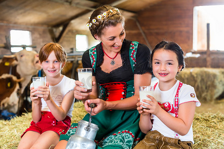 牛仔喝酒摄影照片_巴伐利亚家庭在牛棚里喝牛奶