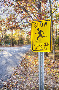 在观看的标志摄影照片_黄色慢儿童在玩耍路标和道路