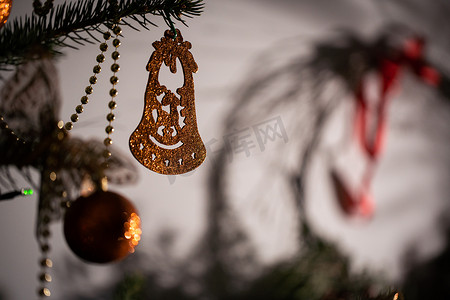 闪亮的钟形装饰品附在背景中的圣诞树上，带有皮质灯。