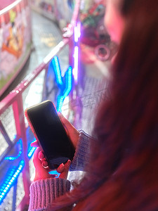 在夜市上拿着手机的女人手的垂直照片