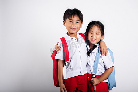 小学生裤子摄影照片_两个亚洲学生孩子女孩男孩小学生兄弟姐妹微笑快乐穿着学生泰国制服红色裤子裙子互相拥抱
