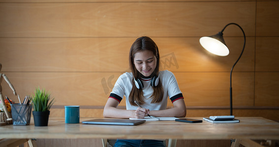 在笔记本电脑上工作或在室内笔记本电脑上学习的女性写作制作列表记笔记的裁剪照片-教育课程或培训、研讨会、在线教育概念。