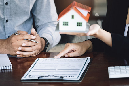 贷款签署概念、再融资、房屋和土地购买、出租住宿、女性房地产经纪人或银行雇员指向与男性客户签订的合同或协议以购买住宅。