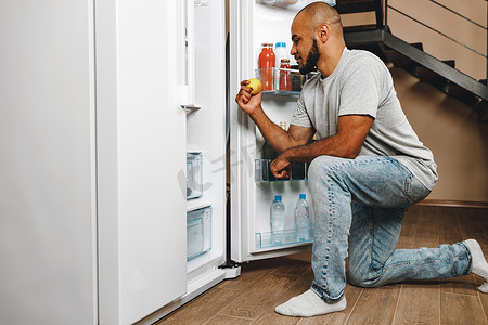 非洲裔美国人从他家的冰箱里拿食物