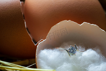 破裂的鸡蛋壳摄影照片_鸡蛋壳中的假钻戒在早晨破裂在卵巢上