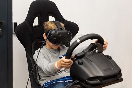 虚拟现实现实摄影照片_这个男孩戴着虚拟现实眼镜在赛车模拟器上玩耍