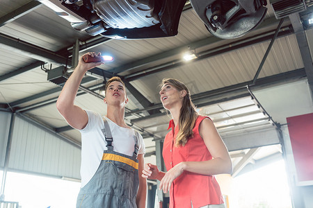 可靠的汽车修理工在现代检查一位女性的汽车