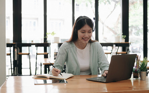 戴着耳机的亚洲女性在笔记本电脑听力学习教育课程电话会议上在线观看网络研讨会播客，在线学习概念。