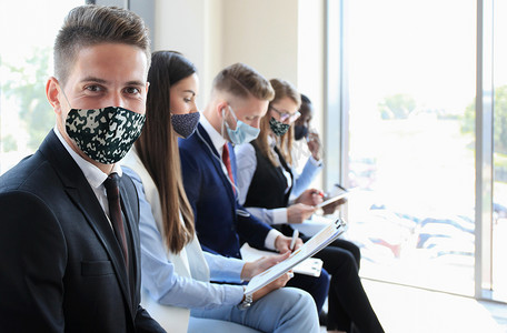 戴着口罩等待面试的压力重重的商界人士，在COVID19期间保持社交距离隔离的影响