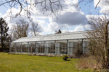 早春的玻璃温室反对多云的天空。